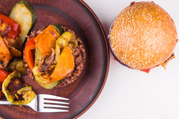 Risotto from red rice with vegetables and a vegetarian sandwich on a white rustic background