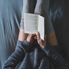 Obraz premium woman read book in bed with gray sheets.
