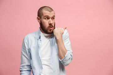 The young man whispering a secret behind her hand over pink background