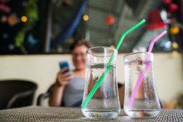 Freshness every day. Glass of very cold water in a transparent glass on the background of the girl with the phone. Quench thirst. Counting calories.