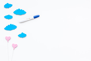 Positive pregnancy test near toy clouds and heart sign on white background top view copy space