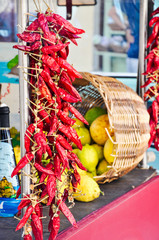 rustic Italian market with fresh fruits, boxes of grapes and oranges, hanging bunches of yellow and red grapes and bunches of chili peppers
