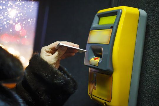 woman punches ticket for trip in the city public transport. Terminal for tickets in the city bus. Payment for travel in transport concept.