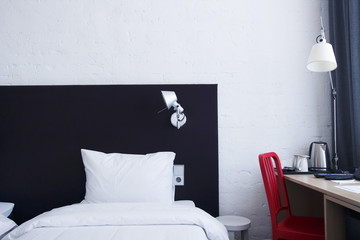 cozy white sleeping bed in the bedroom with night lamp on the table. Bright bedroom in city apartment.