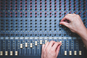 male sound engineer hands working on audio mixing console