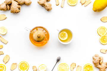 Warming tea with lemon and ginger. Cup, teapot, ginger root on white background top view
