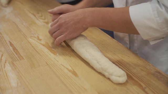 Man kneads the dough for a French loaf in the bakery