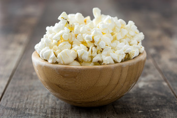 Popcorn in bowl on wooden table background.