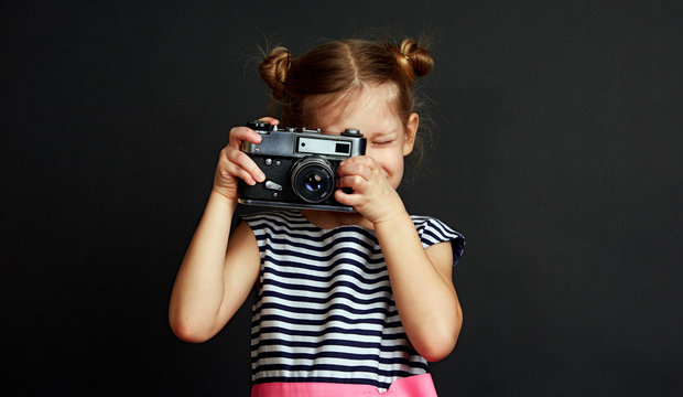 Portrait of cute stylish girl taking photo with old vintage camera. 