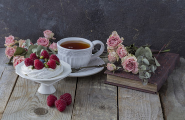 on a wooden table there is a cup of tea, roses, raspberries, cake and heart made of lace