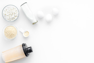 Protein diet for the athlete Scoop of protein near shaker, milk, eggs, cottage cheese on white background top view copy space