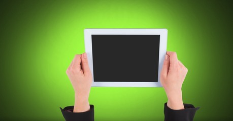 Hand holding tablet with green background