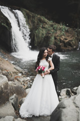 Wedding couple in love kissing and hugging near rocks on beautiful landscape