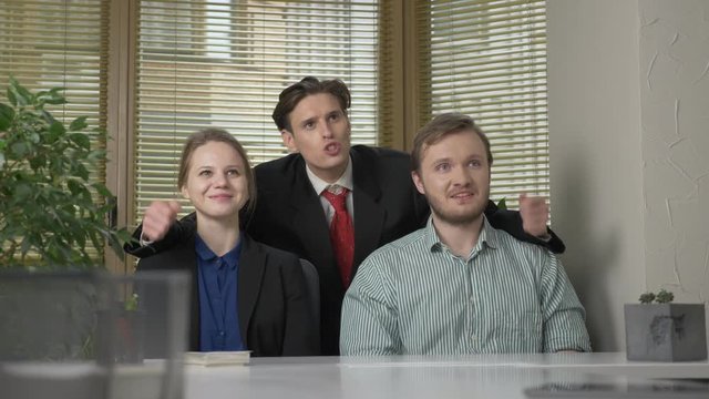 Young man in a suit makes a presentation to two employees of the office. He tells the story impulsively, gestures with his hands. Work in the office concept. 60 fps