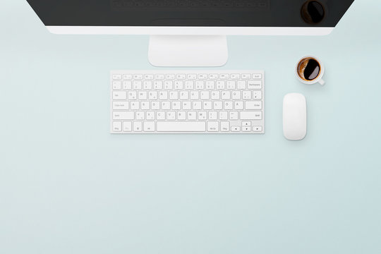 Desktop pc, keyboard, mouse and coffee on blue background with free space for text. Work space, office concept