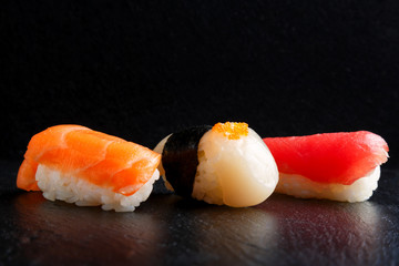 fresh traditional Japanese sushi with scallop, tuna, shrimp on a black background top view. delivery of food from a Japanese restaurant.
