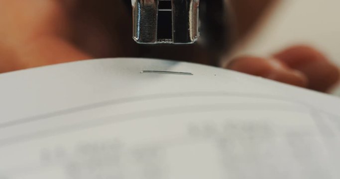 Macro of the stepler doing holes in the paper. Close up of the female hands working.