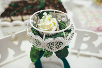 Delicious sweets and cakes decorated with green cream stand served on the candy bar
