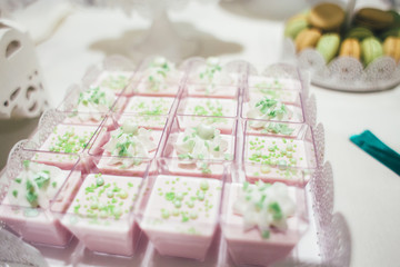 Delicious sweets and cakes decorated with green cream stand served on the candy bar