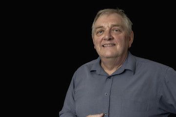 Close up of a happy mature man on a black background, taken with copy space 