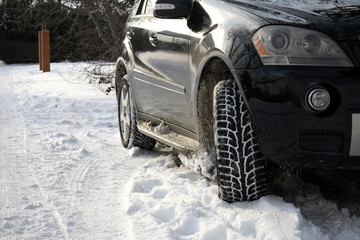 Naklejka premium Close-up portrait of a black car on a snowy road. Black car. Winter. wheels. headlights. white snow. winter nature. power. speed