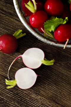 Several red radishes on a wooden board.