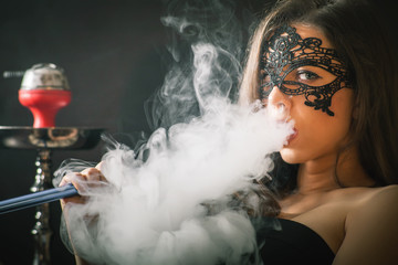 Young, beautiful girl smoke a hookah at club