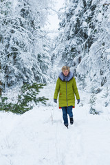 A young woman is walking through the winter forest