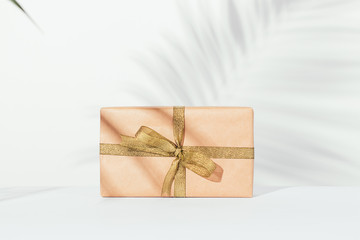 Gift box in wrapping paper with a golden ribbon