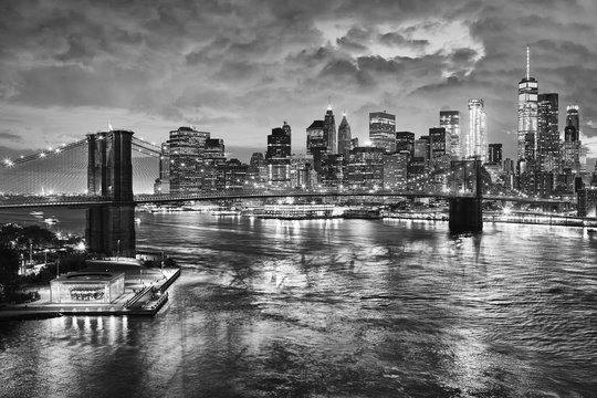 Black and white picture of the Brooklyn Bridge and the Manhattan at night, New York City, USA.