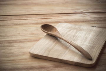 Cutting board and wooden spoon on a wooden table background, vintage