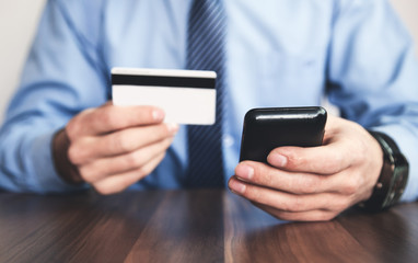 Man holding credit card and using phone.