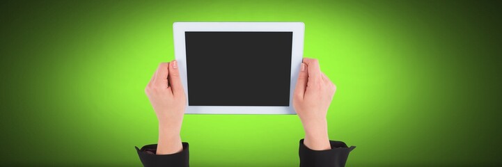 Hand holding tablet with green background