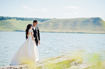 Wedding couple at breathtaking landscape with rock and lake.