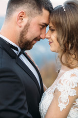 Bride leans to a groom tender standing on the hill with great mountain view behind