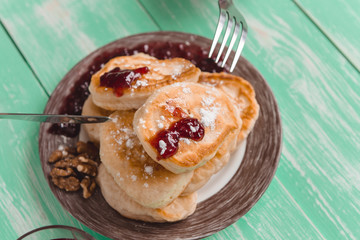 the girl's hands hold a fork and a knife over the plate with pancakes