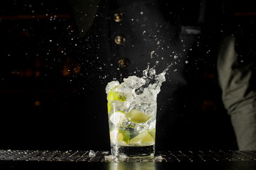 Glass filled with splashing fresh Caipirinha cocktail
