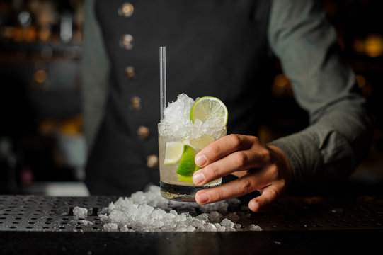 Barman hand holding a glass filled with Caipirinha cocktail