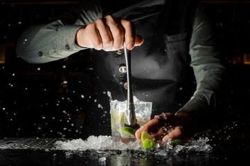Main de barman pressant du jus frais de citron vert faisant un cocktail Caipirinha