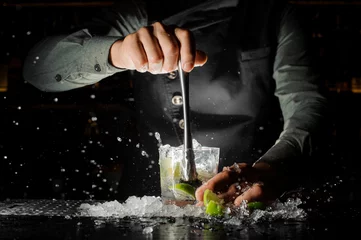 Crédence de cuisine en verre imprimé Cocktail Main de barman pressant du jus frais de citron vert faisant un cocktail Caipirinha