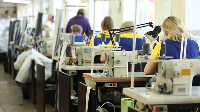 Woman working at a sewing machine, Industrial size textile factory, workers on the production line, industrial interior, needle sewing machine, shallow depth of field