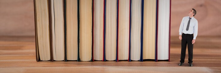 Business man looking up next to books