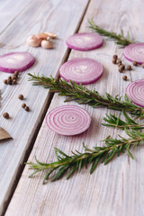 sliced onions and rosemary on white wooden background