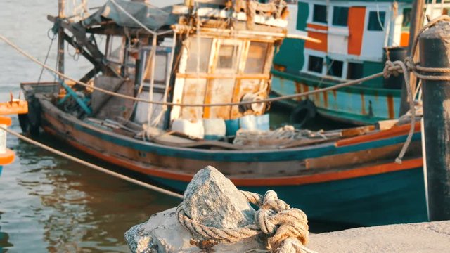 Old wooden half-ruined and wrecked ship is moored on a fishing dock