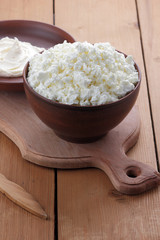 Cheese, cottage cheese and cream in clay ware, fresh curd on a wooden background, rustic sour cream, brown shade, healthy food, French breakfast, top view, goat curd, protein