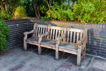 Bank aus Holz an einer Backsteinmauer im Park