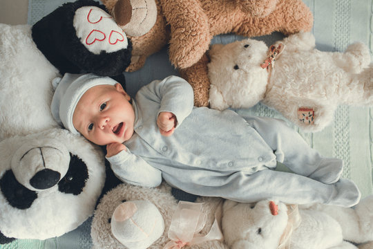 Newborn Baby Laying With Five Teddy Bears On Blanket