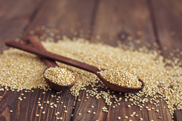 Kinoa seeds in wooden spoons on wooden table