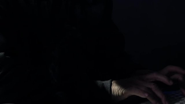 Pan from hands typing to closeup of programmer working hard at night