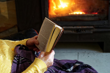 grandma with a book by the fireplace